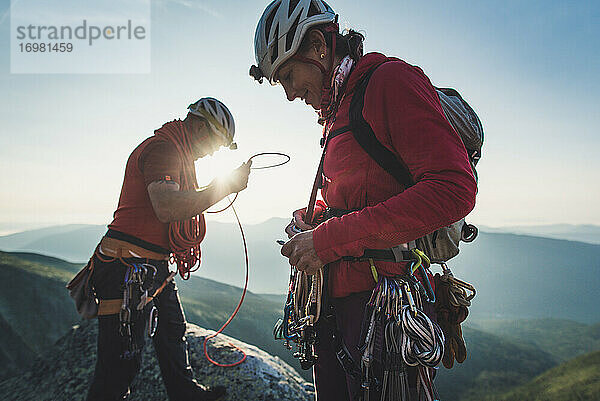 Mann und Frau sortieren Kletterausrüstung am frühen Morgen in den Bergen