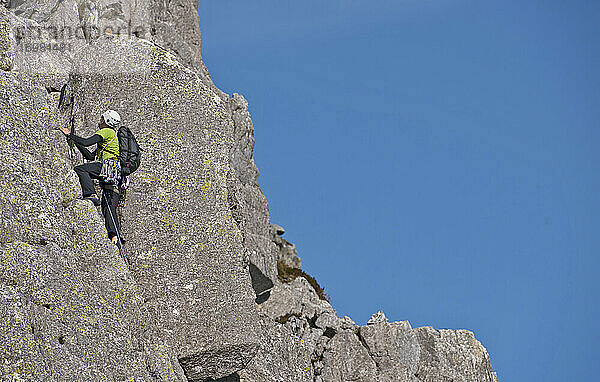 Mann klettert an der Felswand des Tryfan in Nordwales