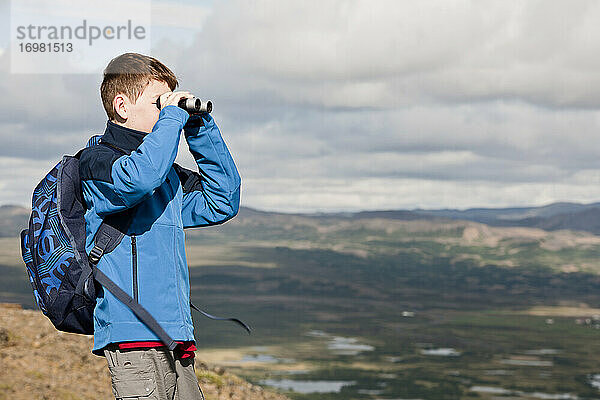 Junge  der mit seinem Fernglas die Landschaft am Myvatn-See betrachtet