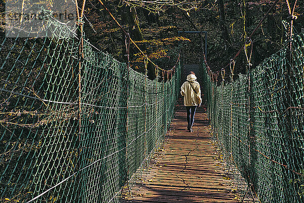 Junge Frau beim Überqueren einer Hängebrücke