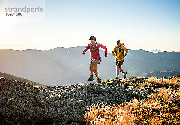 Mann und Frau beim Trailrunning in den Bergen bei Sonnenaufgang
