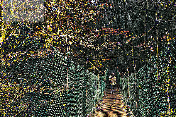 Junge Frau beim Überqueren einer Hängebrücke