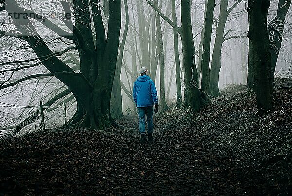 Mann  der im Winter mit seinen Kindern durch einen dunklen englischen Wald geht