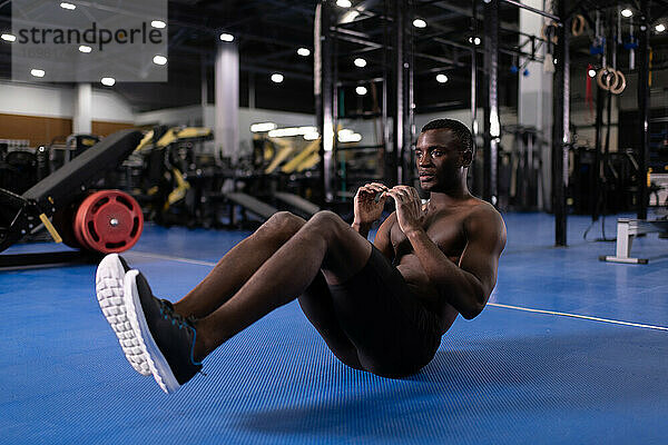 Afroamerikanischer Sportler  der im Fitnessstudio Bauchmuskeln trainiert