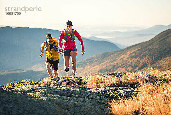 Mann und Frau beim Trailrunning in den Bergen am Morgen