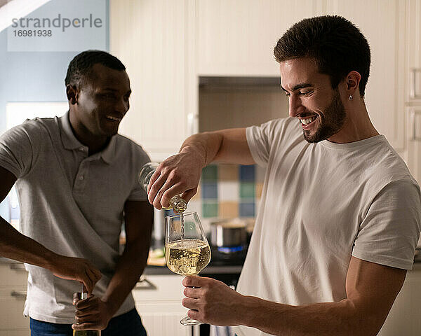 Verschiedene männliche Freunde bereiten Wein für eine Party zu Hause vor
