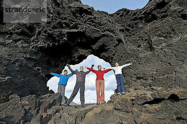 Familie posiert am Natursteinbogen am Myvatn-See in Island