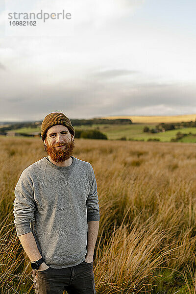 Lächelnder bärtiger Mann in der englischen Landschaft bei Sonnenuntergang