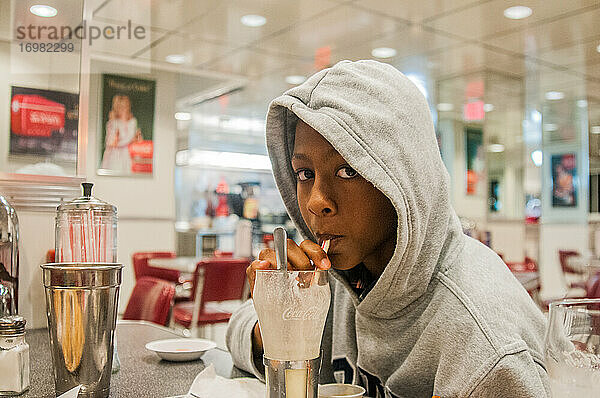 Junger afroamerikanischer Teenager trinkt Milkshake