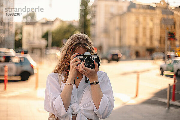 Junge Frau beim Fotografieren auf der Straße in der Stadt im Sommer