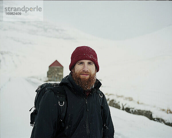 Porträt eines lächelnden  bärtigen Mannes im Schnee  der in die Kamera schaut  auf den Färöer Inseln