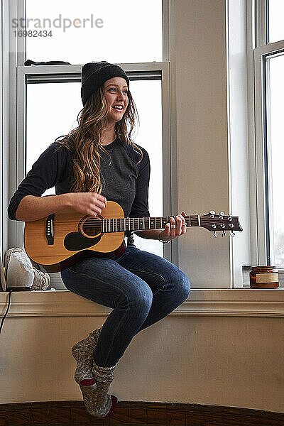 Junge Musikerin spielt Gitarre am Morgen