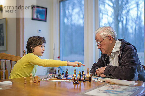 Ein Junge macht einen Schachzug  während sein Großvater zusieht
