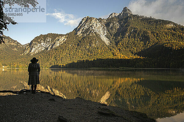 Eine Frau steht im Schatten eines Berges am See in Deutschland