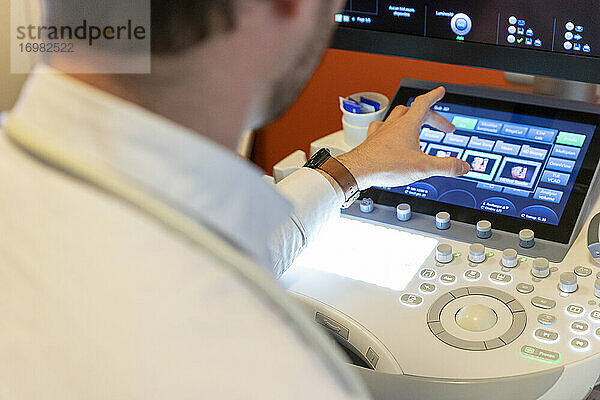 Aufnahme der Hand eines Pflegers  der die Tastatur eines Ultraschallgeräts bedient