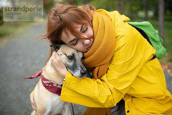 Junge Frau umarmt Hund auf der Straße