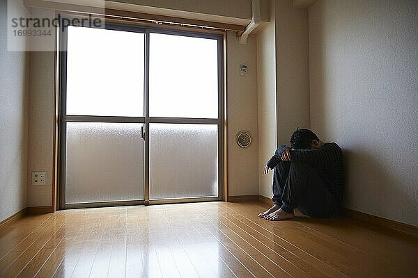 Trauriger japanischer Mann in leerer Wohnung