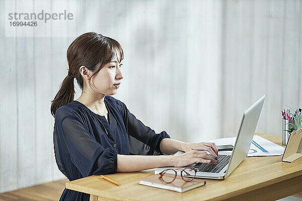 Junge japanische Geschäftsfrau arbeitet an ihrem Laptop