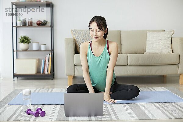 Gesunde japanische Frau trainiert zu Hause