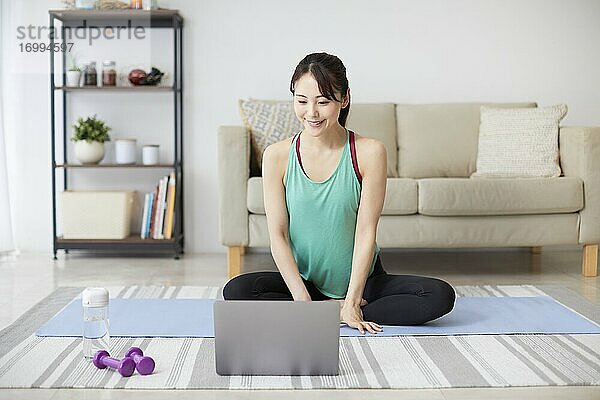 Gesunde japanische Frau trainiert zu Hause