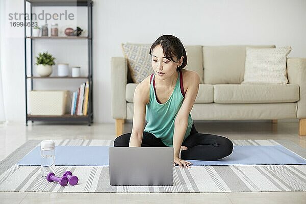 Gesunde japanische Frau trainiert zu Hause
