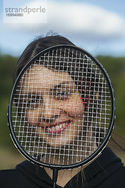 Porträt glückliche junge Frau hinter Badmintonschläger