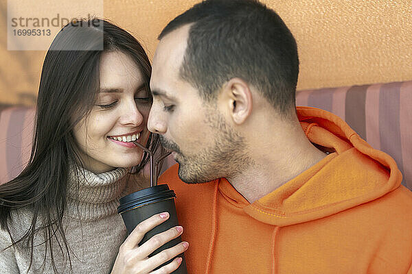 Romantisches junges Paar teilt Kaffee mit Strohhalmen