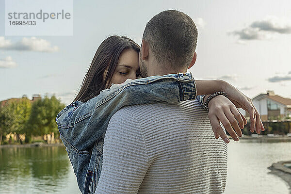 Gelassenes  zärtliches junges Paar  das sich am See umarmt
