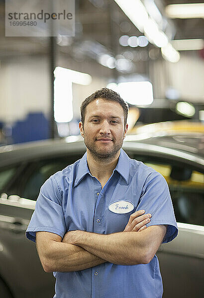 Automechaniker in einer Reparaturwerkstatt  junger weißer Mann in Uniform mit Namensschild