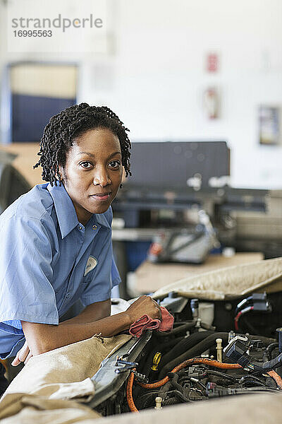 Porträt einer lächelnden schwarzen Mechanikerin in einer Autowerkstatt