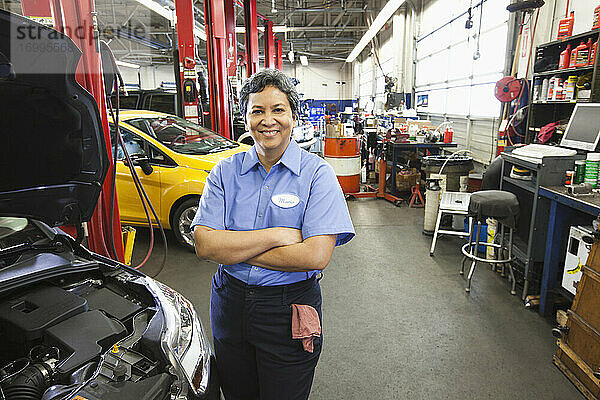 Porträt einer hispanischen Mechanikerin in einer Autowerkstatt