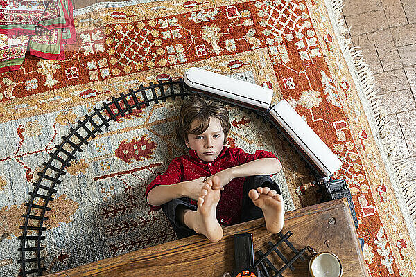 Draufsicht auf einen kleinen Jungen  der mit seiner Eisenbahn spielt