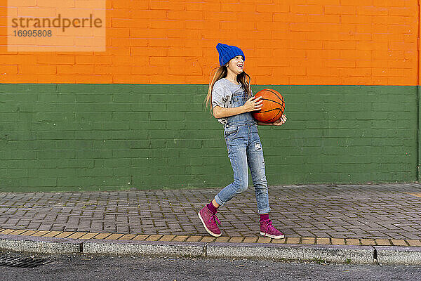 Junges Mädchen spielt Basketball  lachend
