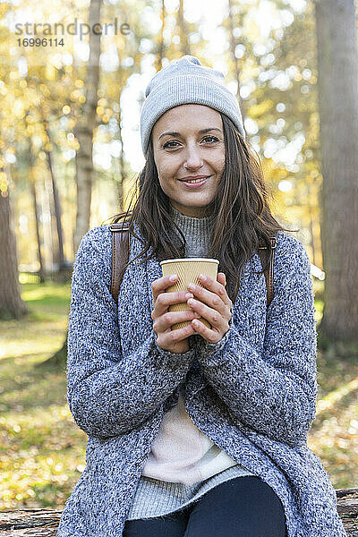 Lächelnde Wanderin mit Teetasse in den Wäldern von Cannock Chase im Winter