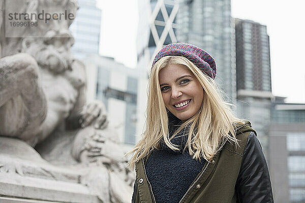 Blonde Frau lächelt  während sie in der Stadt steht