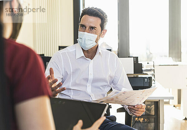 Geschäftsleute mit Gesichtsmaske bei einer Besprechung im Büro