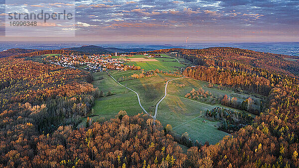 Deutschland  Baden-Württemberg  Drohnenansicht eines Dorfes inmitten eines Herbstwaldes in der Morgendämmerung