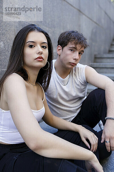 Junger Mann und Frau starren sich an  während sie auf einer Treppe sitzen