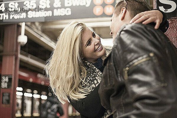 Lächelnde Freundin  die ihren Freund umarmt  während sie in der U-Bahn-Station steht