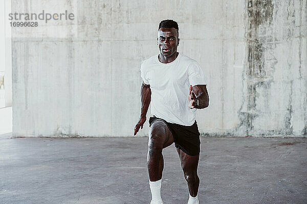 Aktiver männlicher Sportler  der gegen eine weiße Wand läuft
