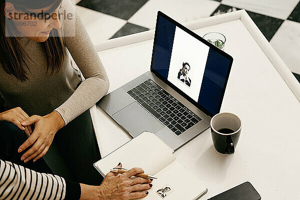 Tochter schaut sich ein Schwarz-Weiß-Foto auf dem Laptop an  während sie bei ihrer Mutter zu Hause sitzt