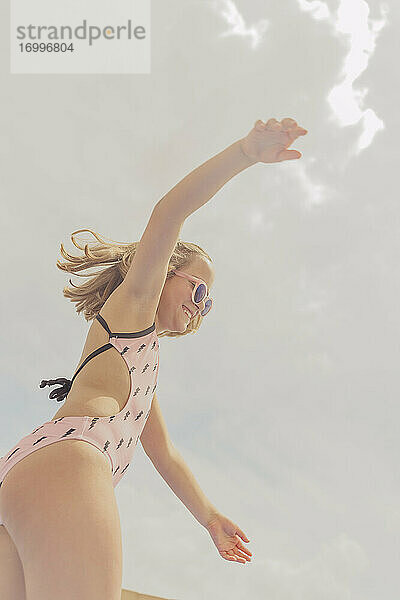 Glückliches Mädchen mit rosa Sonnenbrille und Badeanzug hat Spaß
