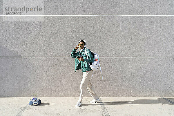 Junger Mann mit Kopfhörern und Mobiltelefon  der eine Tasche trägt  während er tanzt - kein Fußweg