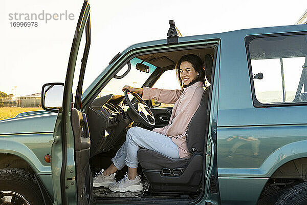 Lächelnde junge Frau im Auto sitzend während einer Autoreise