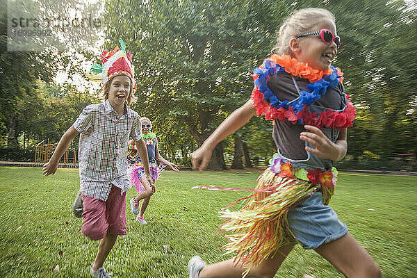 Fröhliche Kinder in Kostümen laufen im Park