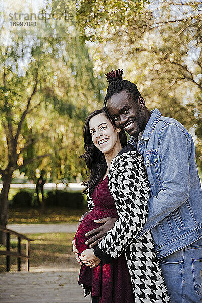 Glückliche schwangere Frau steht mit Mann im Park