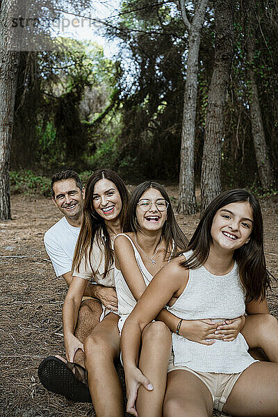 Glückliche Familie in Reihe sitzend im Wald im Urlaub