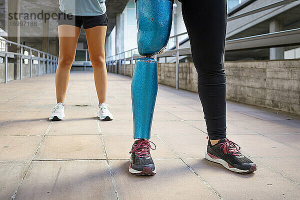 Sportlerin mit Beinprothese steht mit Freund auf Brücke