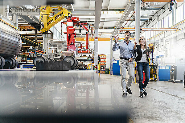 Geschäftsmann und weibliche Kollegin  die in einer Fabrik ein digitales Tablet halten