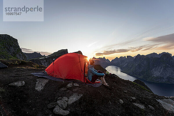 Frau im Lager auf einem Berg bei Sonnenuntergang in Reinebringen. Lofoten  Norwegen